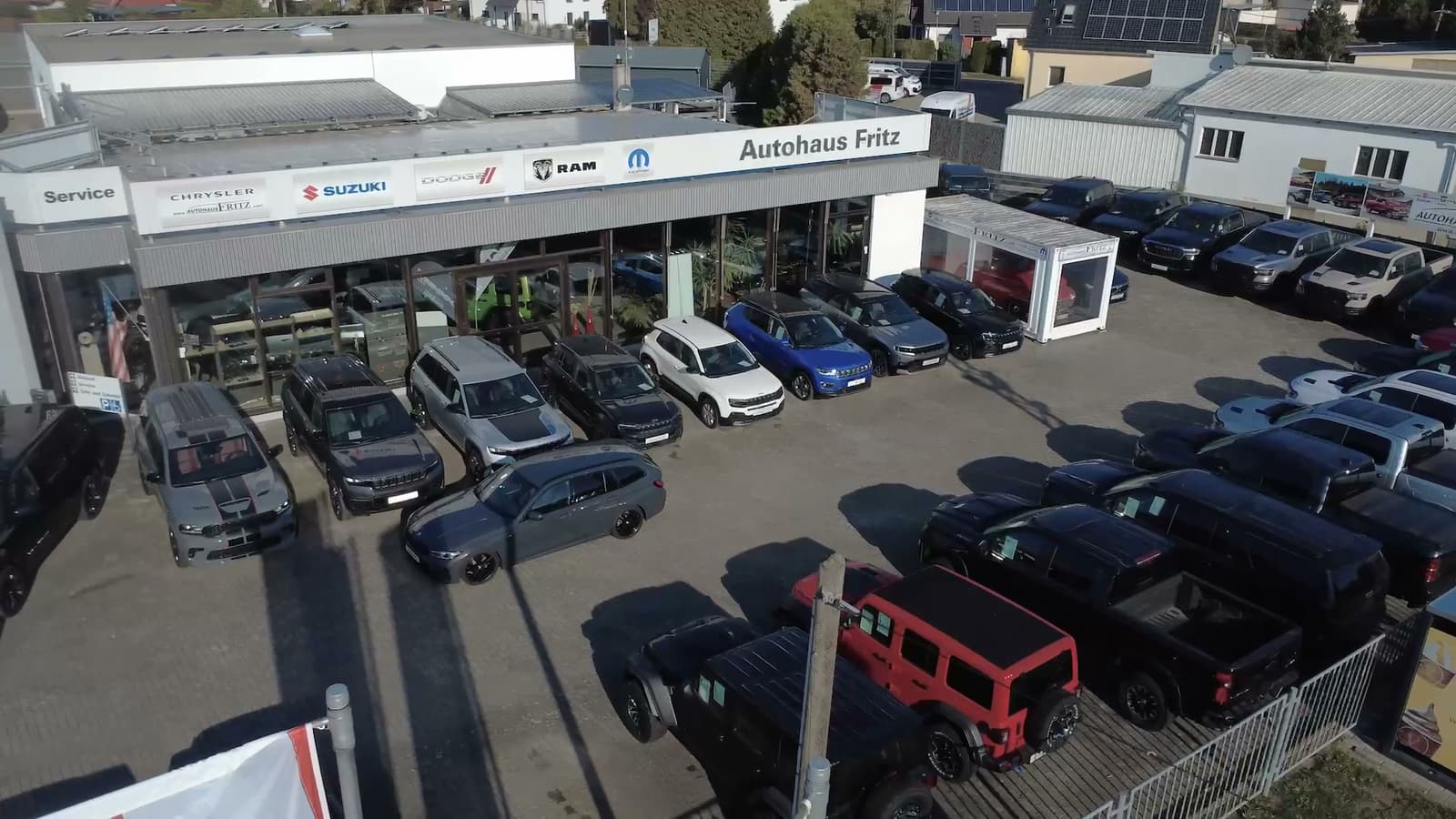 Das Autohaus Fritz in Oppin von oben: Verkaufsgebäude mit Markenschildern und dem Schriftzug Autohaus Fritz, davor eine Reihe Fahrzeuge