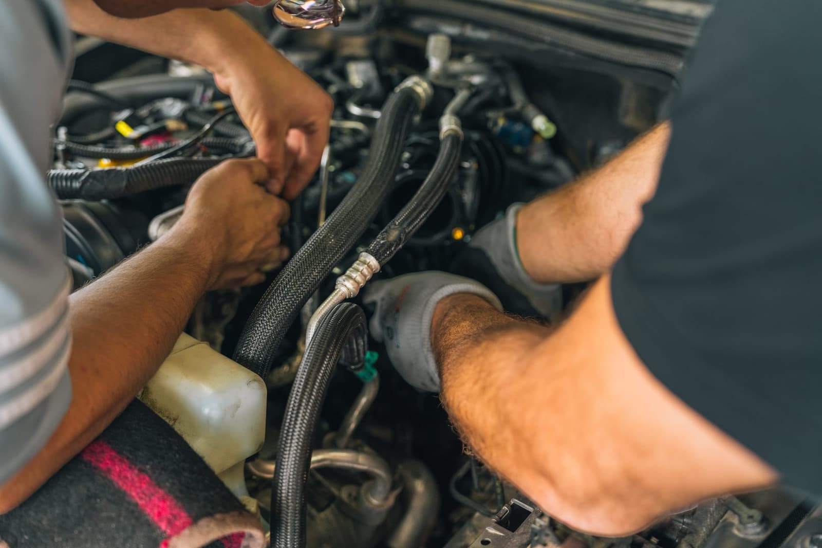 Hände eines Mechanikers bei der Arbeit am Motorraum